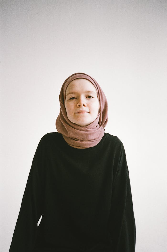 Studio portrait of a confident young woman wearing a hijab, with a neutral background.
